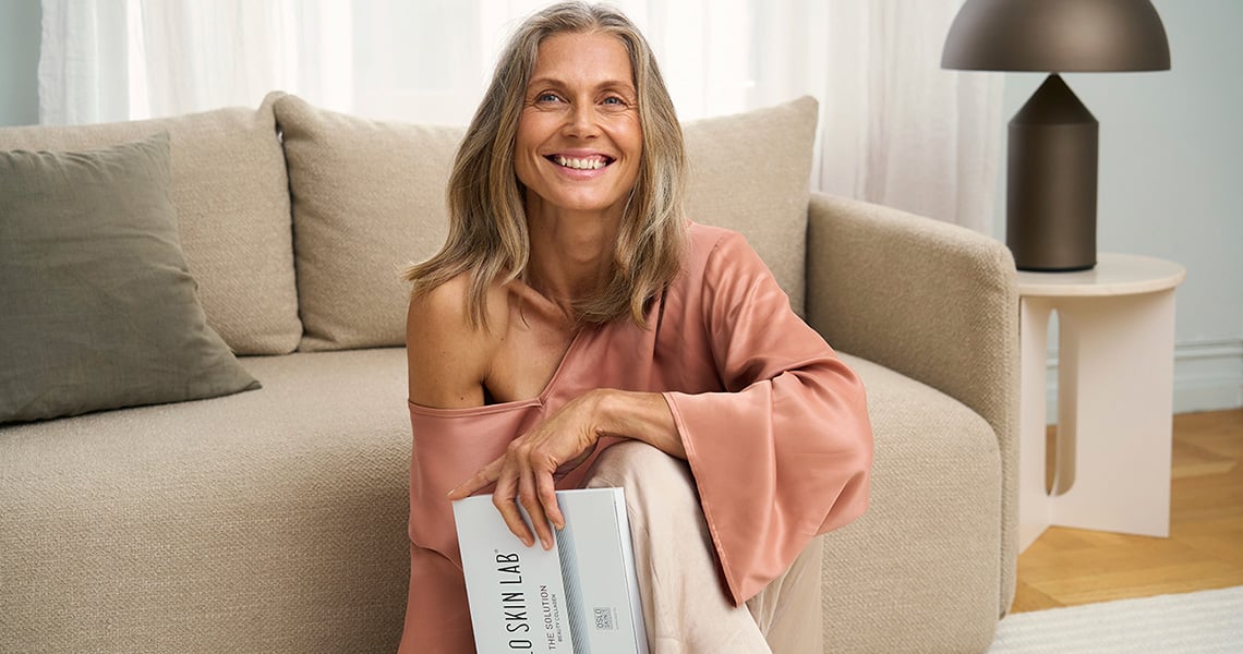 En kvinne som sitter foran en sofa og holder en eske med «The Solution» i hånden